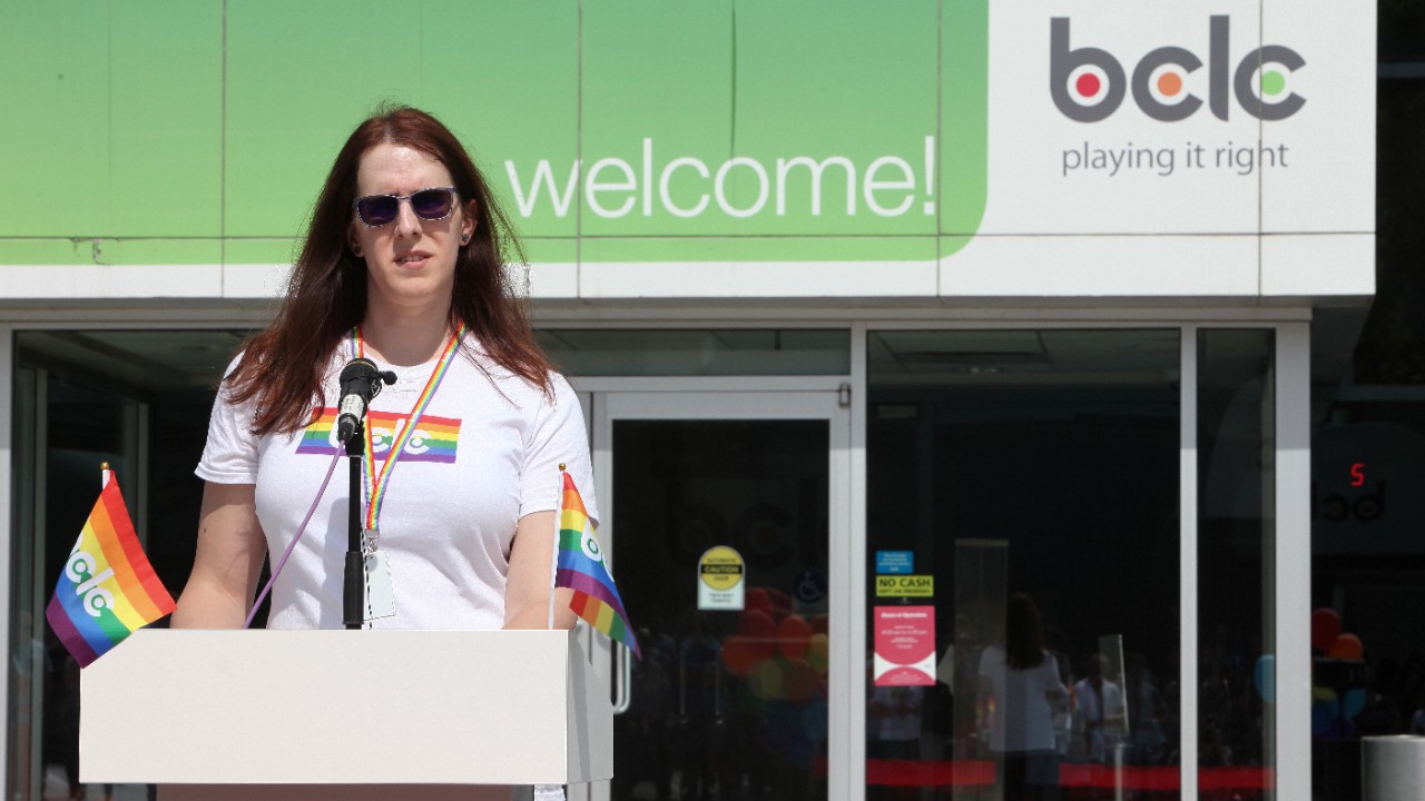 Speaker at podium with small PRIDE flag