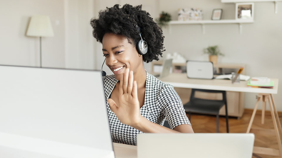 Woman waving at computer screen