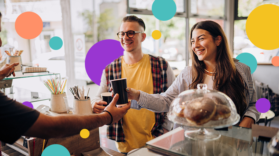 Two people at a coffee shop register, talking to barista